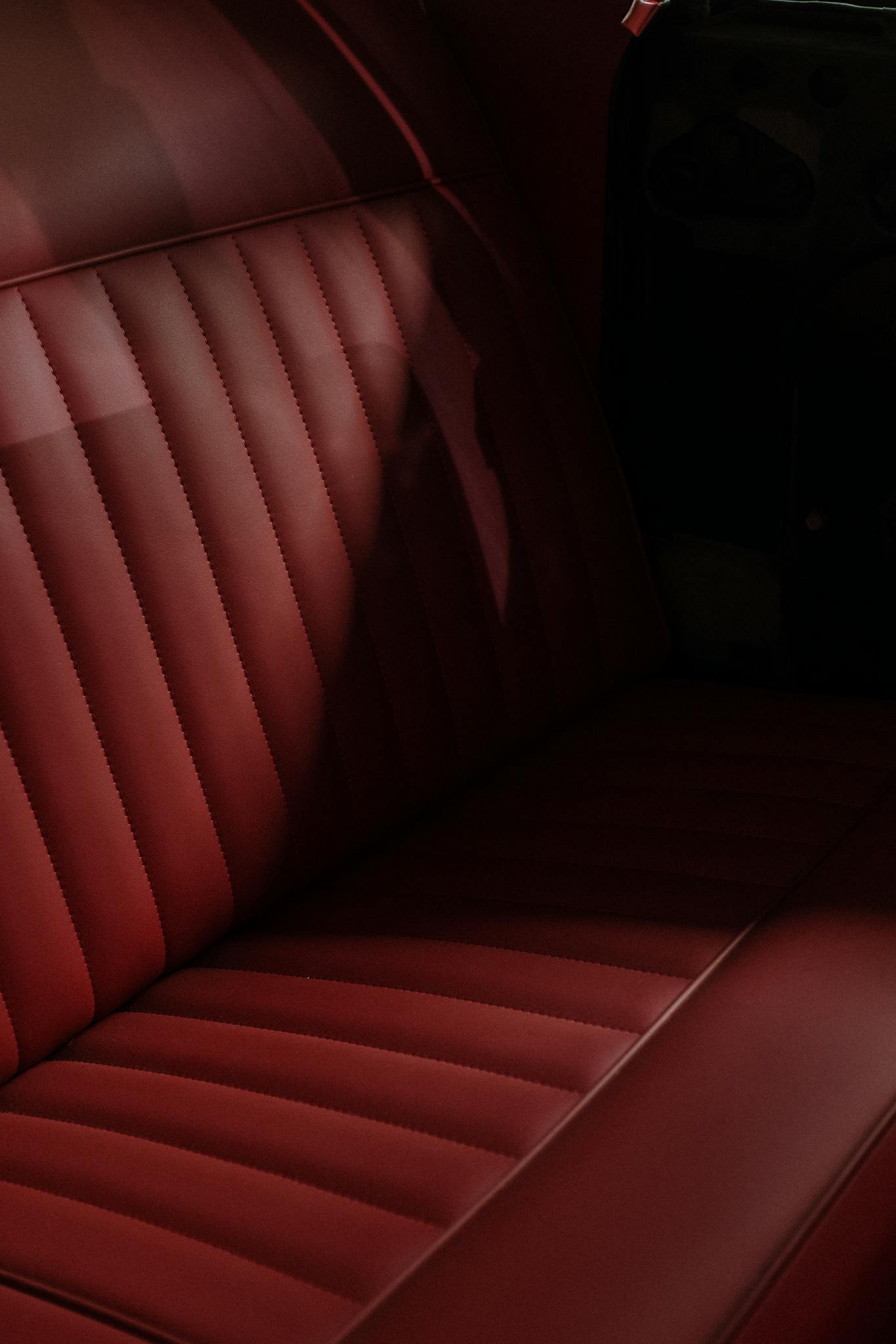 Close-up of a classic car's interior featuring red leather seats with retro styling.