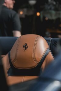 Close-up of a luxurious tan leather car seat with branding in focus.