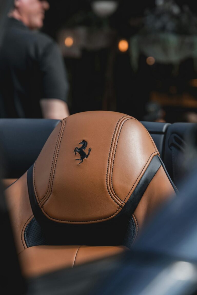 Close-up of a luxurious tan leather car seat with branding in focus.
