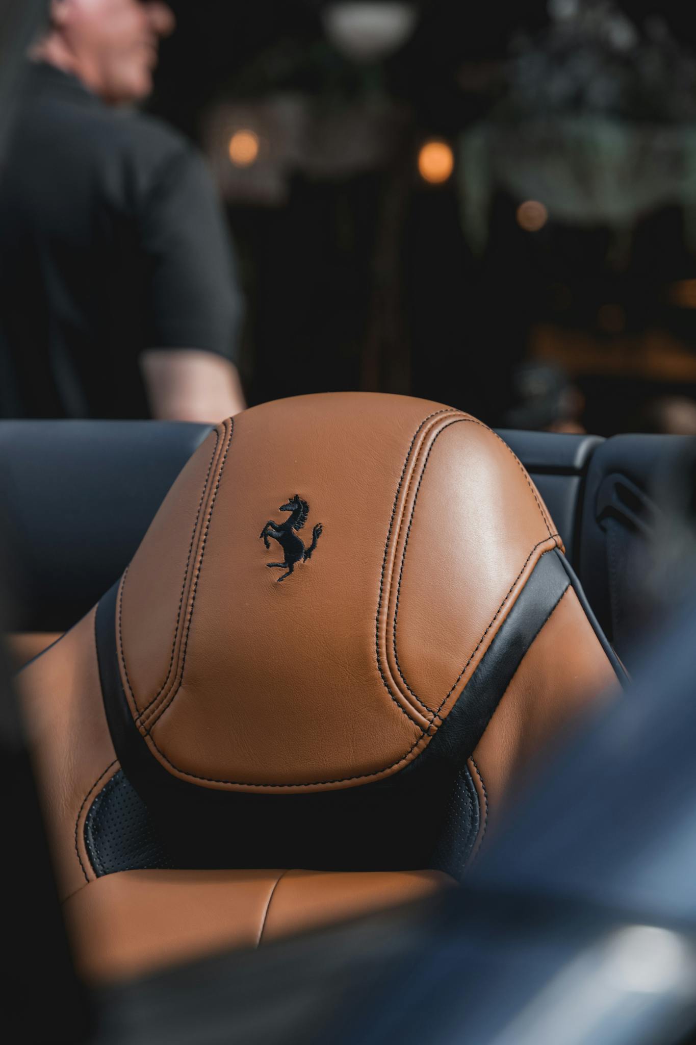 Close-up of a luxurious tan leather car seat with branding in focus.